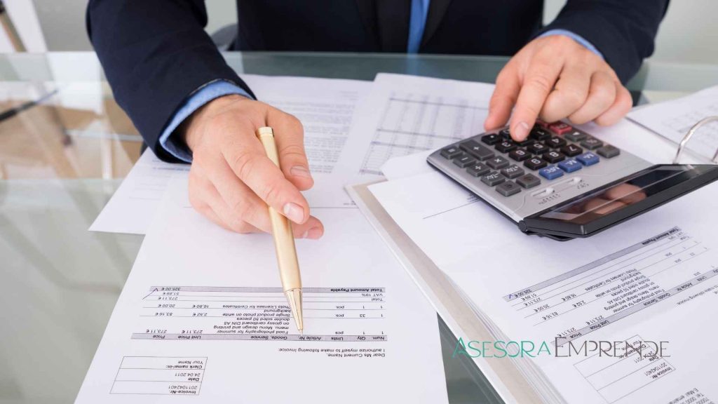 Persona revisando facturas en papel con calculadora, representando cómo los autónomos deben adaptarse a Verifactu en 2026 para cumplir con Hacienda.